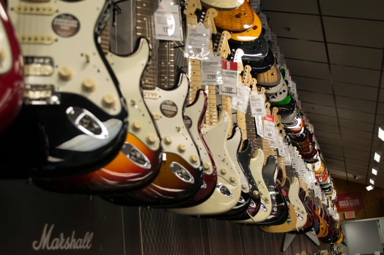 a room filled with lots of guitars hanging from the ceiling, unsplash, fender stratocaster, the store, thumbnail, left profile