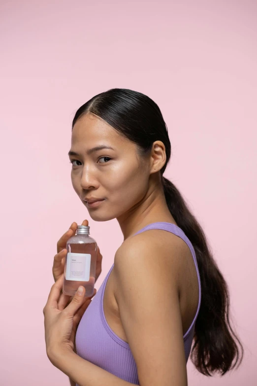 a woman in a purple top holding a bottle of perfume, inspired by Ruth Jên, clear facial details, pokimane, modeled, front on
