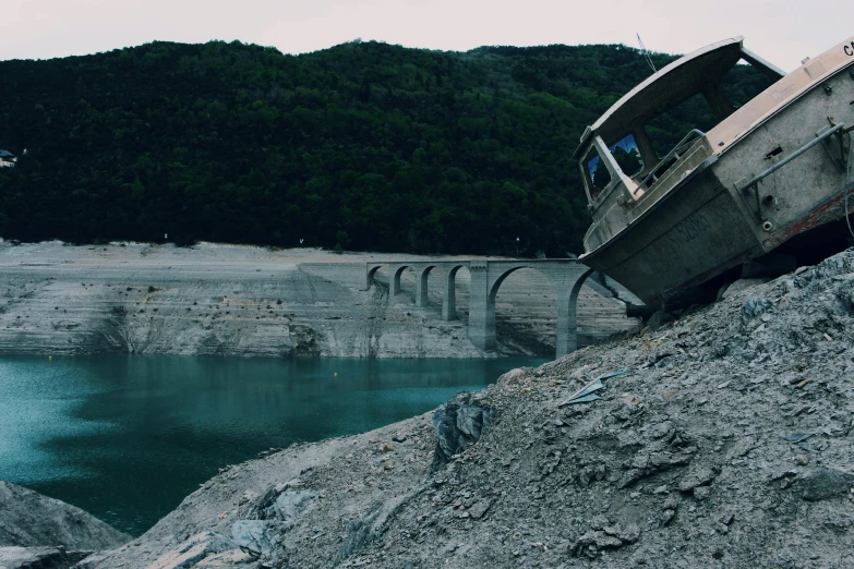 a boat sitting on top of a rock next to a body of water, pexels contest winner, auto-destructive art, landslides, broken bridges, cybertruck, 1990's photo