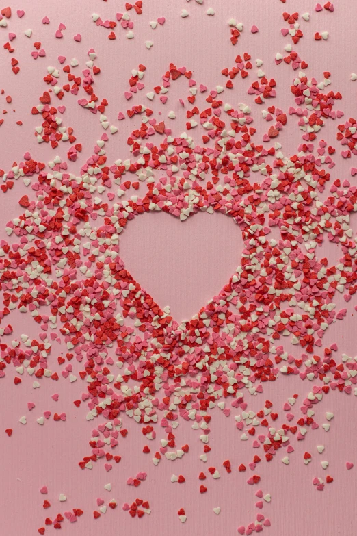 a heart surrounded by confetti sprinkles on a pink background, by Valentine Hugo, pexels, jen atkin, made of candy, adafruit, 256435456k film