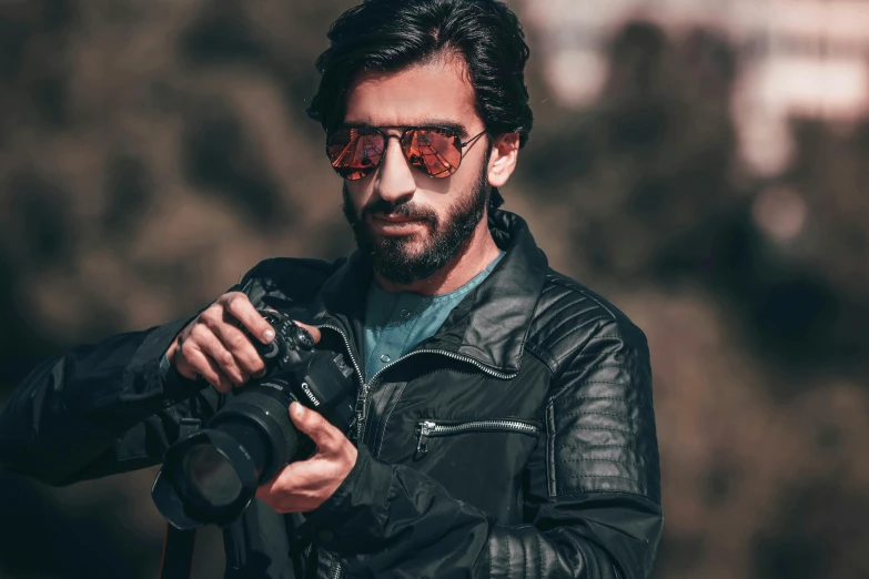 a man in a leather jacket holding a camera, pexels contest winner, wearing oakley sunglasses, eng kilian, avatar image, attractive photo