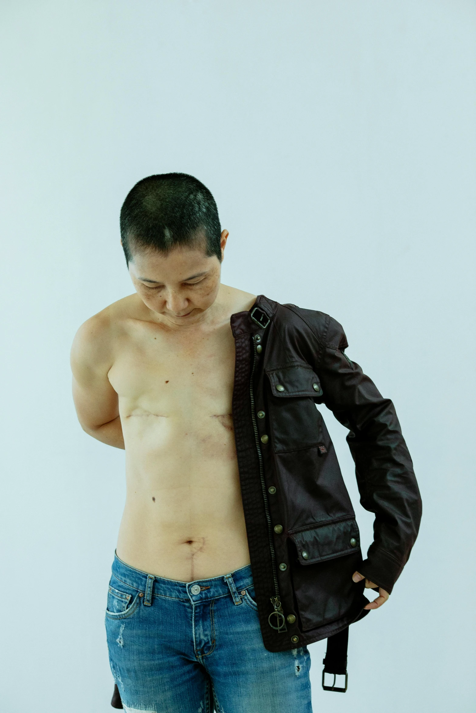 a shirtless man holding a jacket over his chest, an album cover, inspired by Zhang Kechun, flickr, hyperrealism, battle scars across body, 30 years old woman, shinichi fukuda, taken in the late 2010s