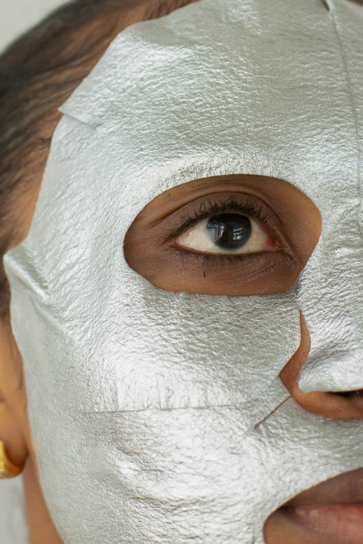 a close up of a person wearing a face mask, inspired by Marina Abramović, gleaming silver, slightly tanned, issey miyake, diverse