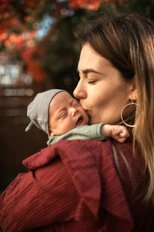 a woman holding a baby in her arms, by Daniel Lieske, pexels, lovely kiss, high quality portrait, holiday, multiple stories