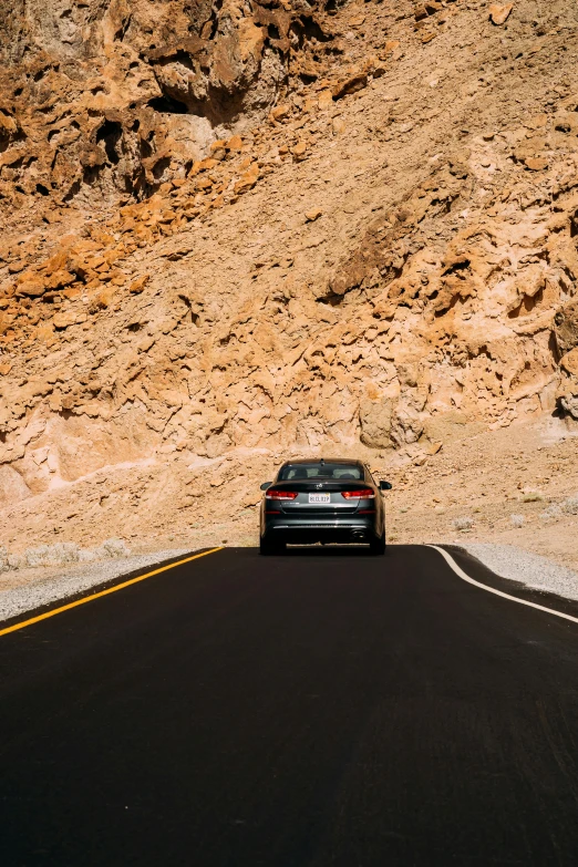 a car that is sitting on the side of a road, by Julia Pishtar, pexels contest winner, crossing the desert, rear facing, landslide road, bmw