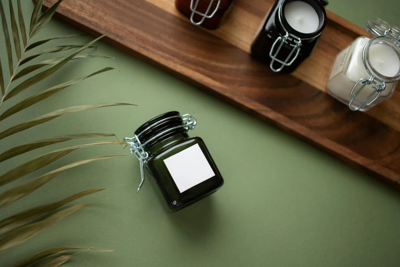 a couple of jars sitting on top of a wooden tray, a still life, unsplash, black and green scheme, skincare, angled, small square glasses