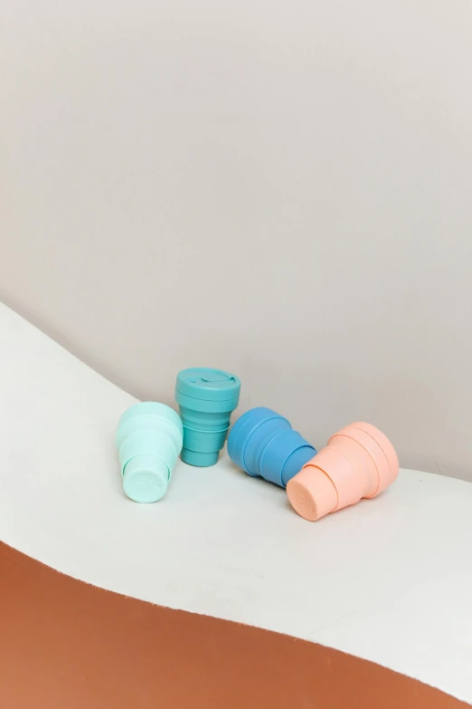 a couple of cups sitting on top of a table, silicone skin, sherbert sky, stacked, three quarter shot