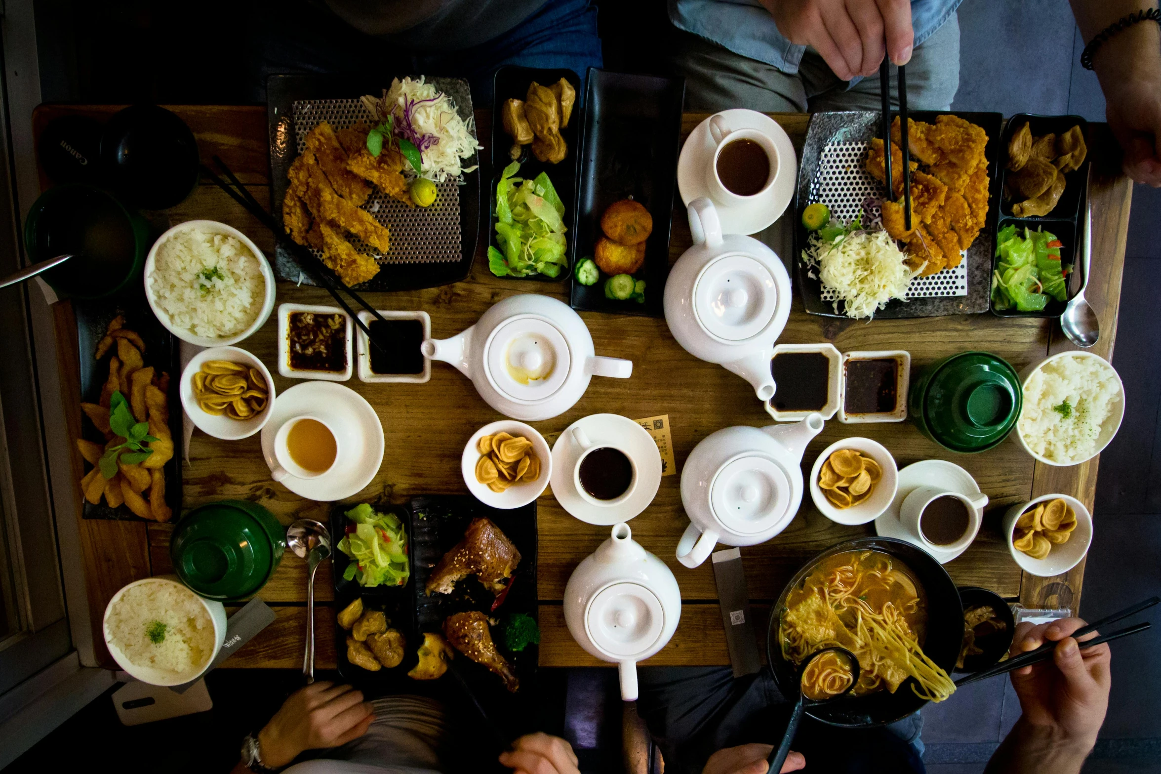 a group of people sitting at a table with plates of food, trending on unsplash, mingei, square, south east asian with long, tea, high quality image