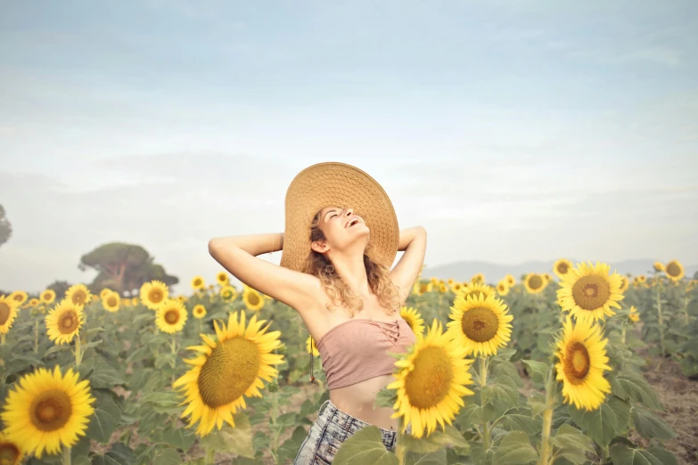 a woman standing in a field of sunflowers, inspired by Sun Long, pexels contest winner, with straw hat, floating in air, relaxed expression, without text