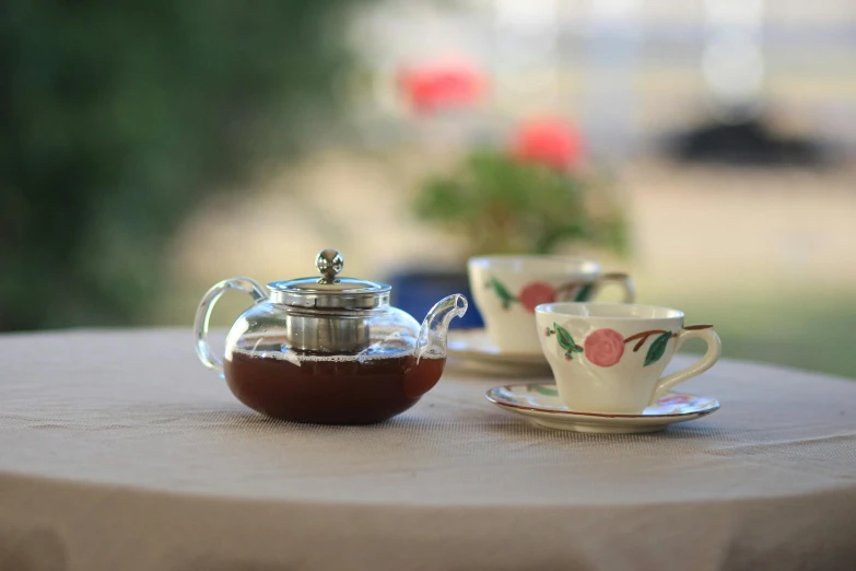 a tea pot sitting on top of a table next to a cup and saucer, inspired by Elsa Beskow, unsplash, square, at the terrace, manuka, 3 - piece