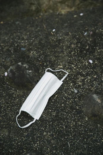a white face mask laying on the ground, unsplash, plasticien, multiple stories, low quality photo, shoreline, gray canvas