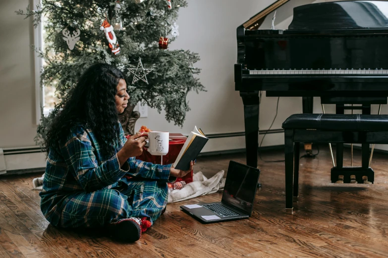 a woman sitting on the floor reading a book, by Julia Pishtar, pexels, christmas, coffee and musical instrument, avatar image, sitting at a computer