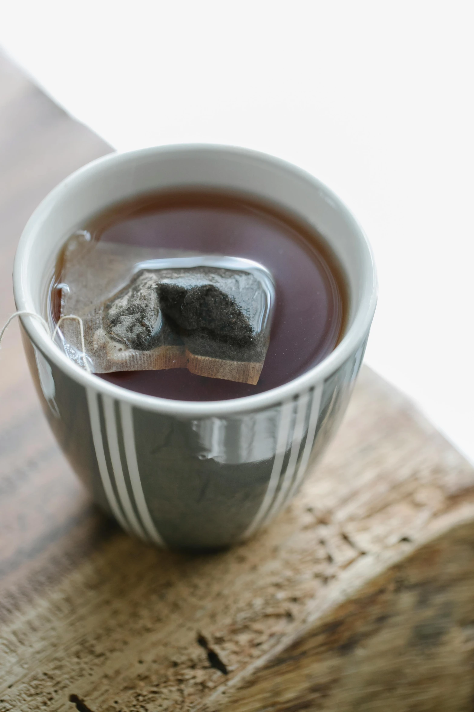 a cup of tea sitting on top of a wooden table, charcoal and silver color scheme, square, promo image, edible