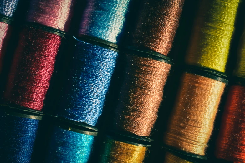 a close up of a bunch of spools of thread, by Thomas Häfner, unsplash, arts and crafts movement, iridescent details, thumbnail, 1920s gaudy color, shimmer detailed