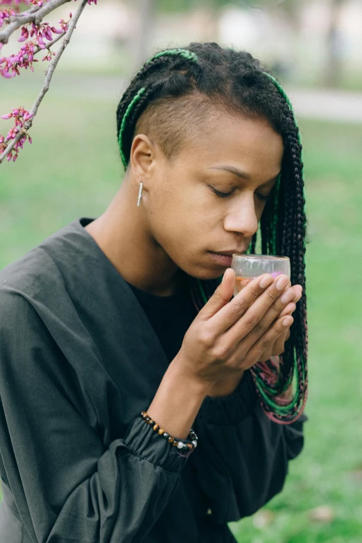 a close up of a person holding a cell phone, inspired by Carrie Mae Weems, trending on unsplash, renaissance, drinking tea, portrait of a female druid, smelling good, outdoors