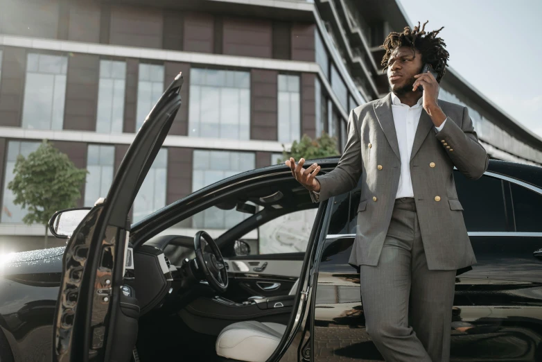 a man standing next to a car talking on a cell phone, pexels contest winner, renaissance, black luxurious suit, chief keef, professional sports style, 1 4 9 3
