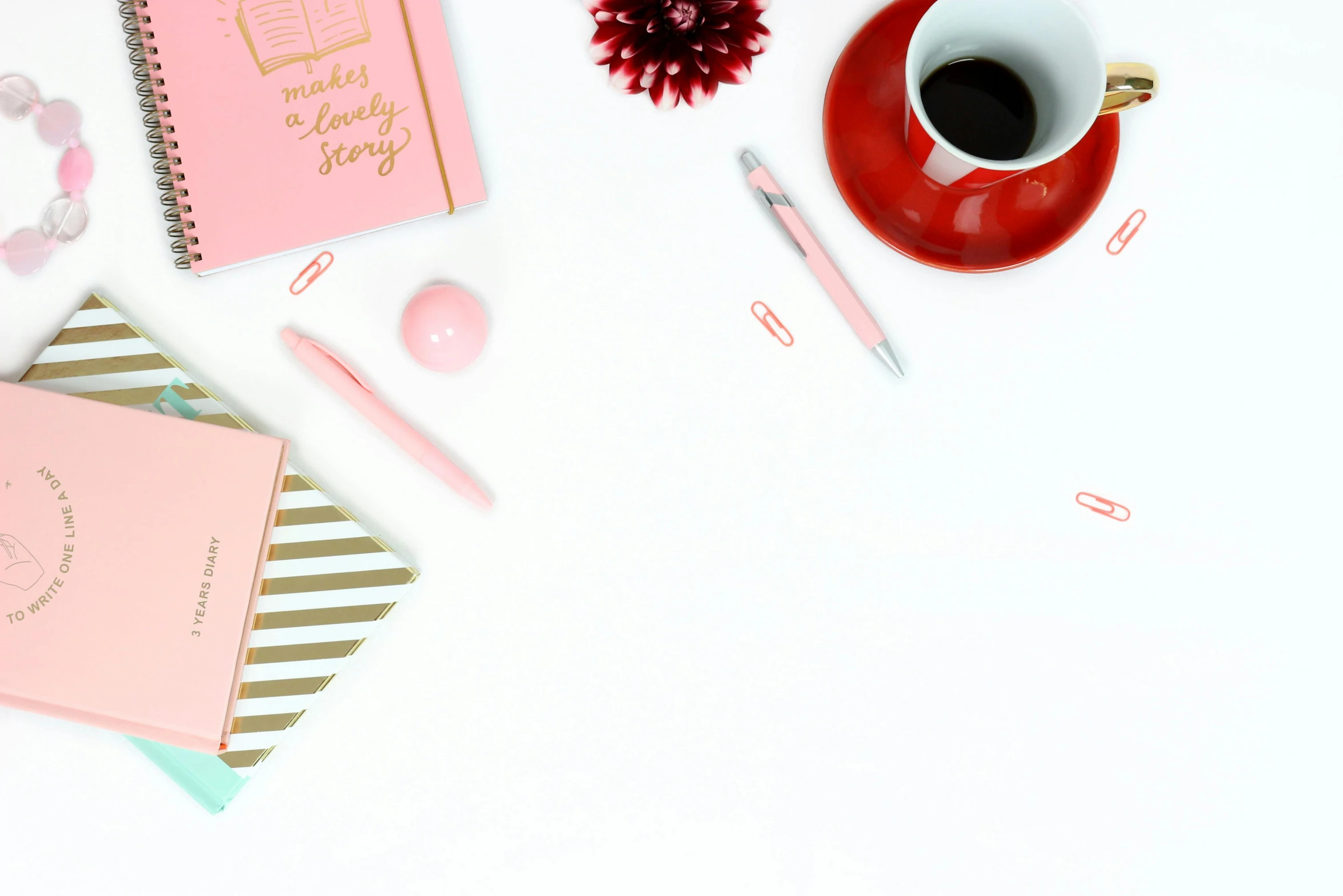 a pink notebook sitting on top of a table next to a cup of coffee, trending on pexels, white and red color scheme, background image, multiple stories, on a white background