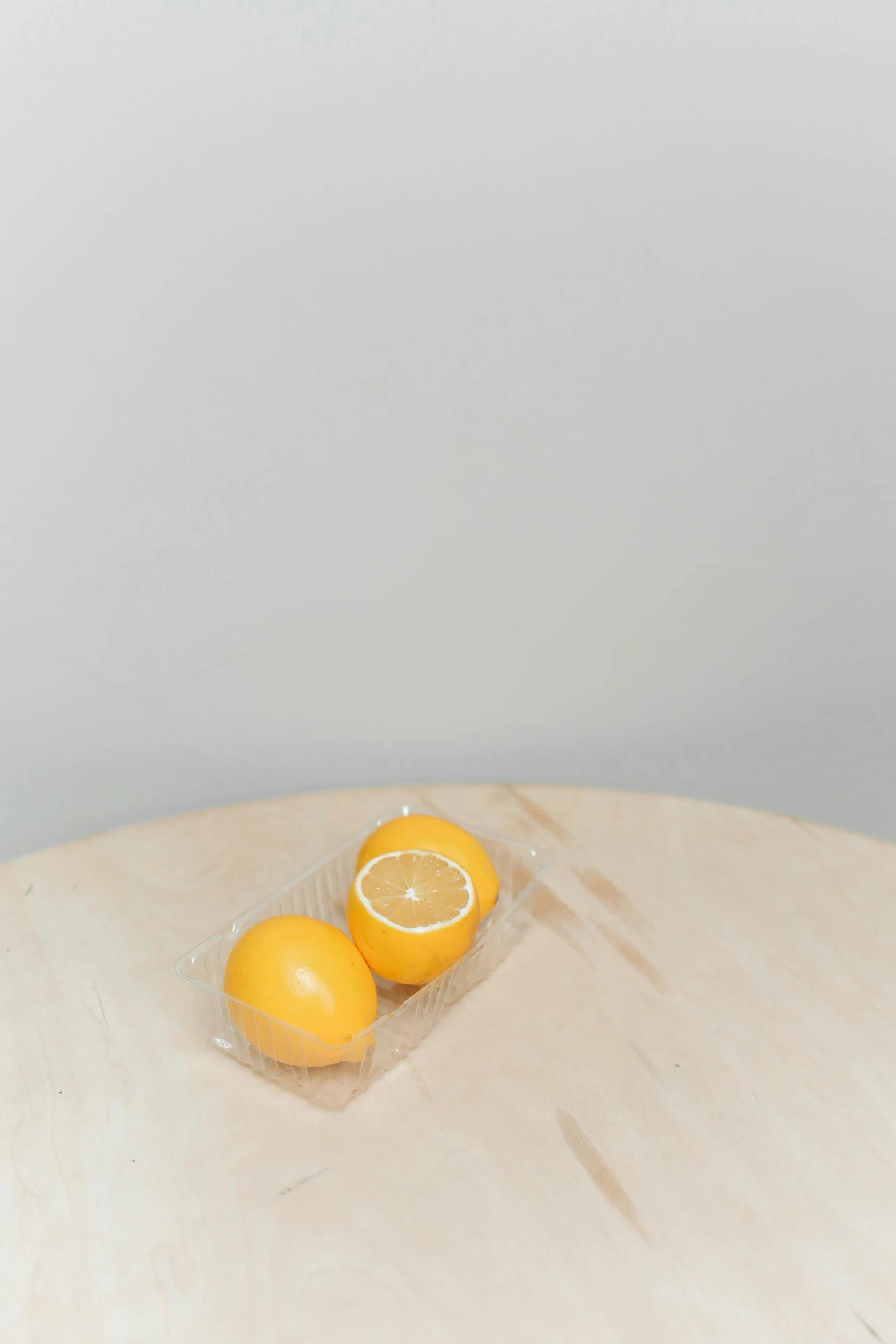 two lemons sitting on top of a wooden table, by Harvey Quaytman, soft vinyl, oranges, 6 pack, plastic wrap