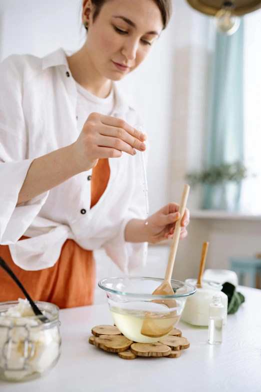 a woman standing in a kitchen preparing food, inspired by Yukimasa Ida, trending on pexels, melted wax, white background, butter, square