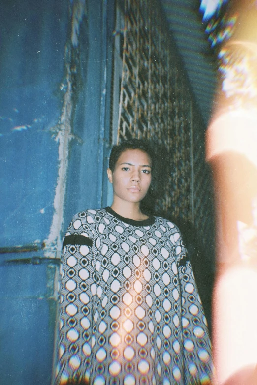 a woman standing in front of a blue door, a polaroid photo, inspired by Elsa Bleda, happening, patterned clothing, asian woman, dolman, very very low quality picture