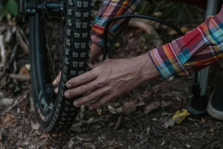 a close up of a person putting a tire on a bike, adventure gear, patterned, hands straight down, press shot