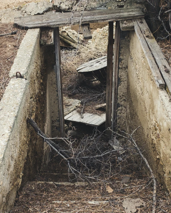 a wooden door sitting in the middle of a dirt field, an album cover, unsplash, land art, look down a cellar staircase, debris, tar pits, ignant