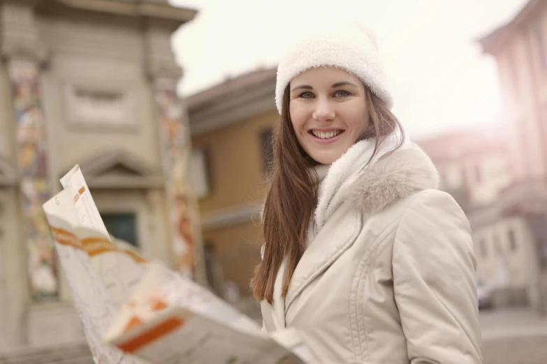 a woman in a white hat is holding a map, wearing a white winter coat, all roads lead to rome, warm friendly face, thumbnail