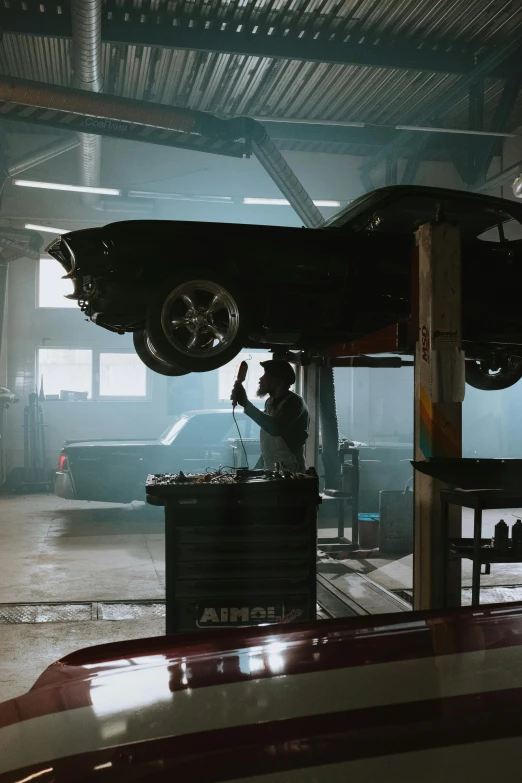 a man working on a car in a garage, inspired by Elsa Bleda, pexels contest winner, iconic scene, black car, lifted, octane 4k