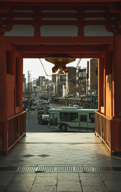 a bus that is sitting in front of a building, a picture, inspired by Torii Kiyomasu, unsplash, sōsaku hanga, view from back, archway, square, detailed cinematic shot