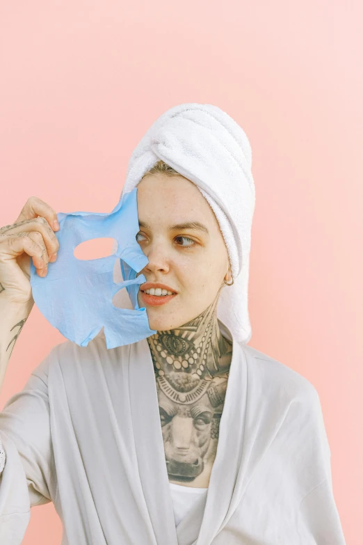 a woman with a towel wrapped around her head, inspired by Elsa Bleda, trending on pexels, antipodeans, with facial tattoo, pastel blue, paper cut out, skimask