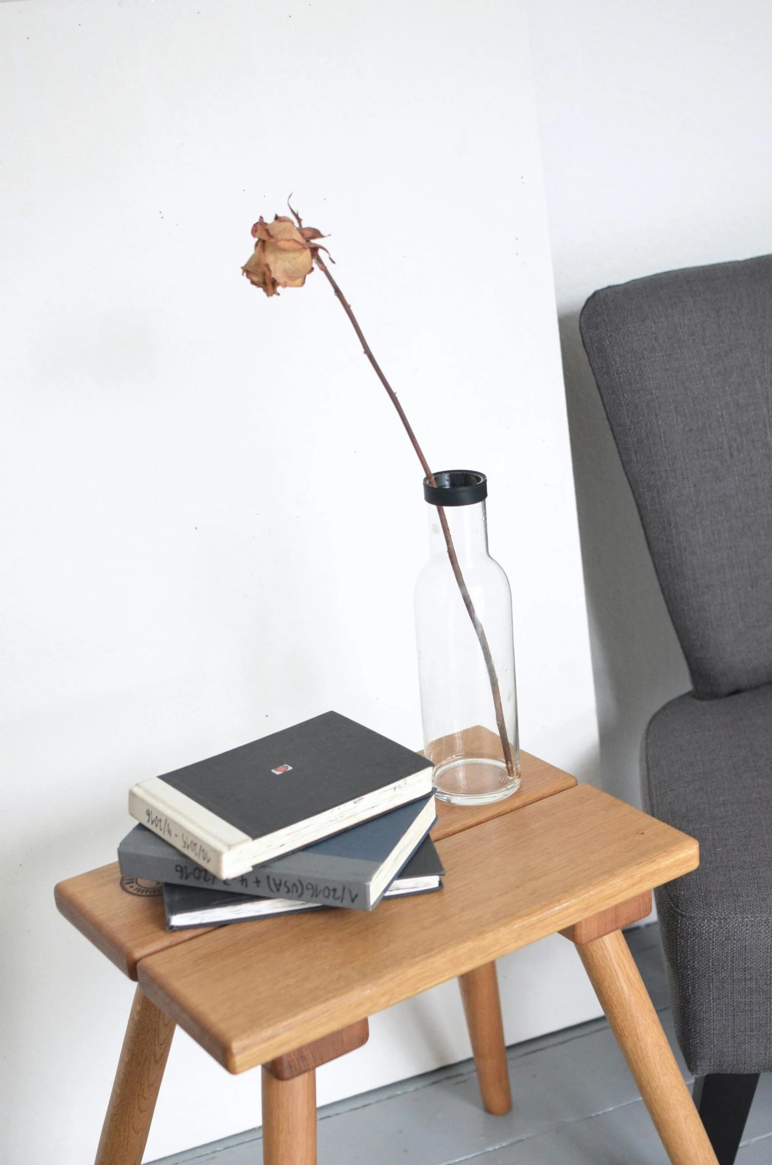 a small table with books and a vase on it, black rose, japanese collection product, candid shot, 3 pm