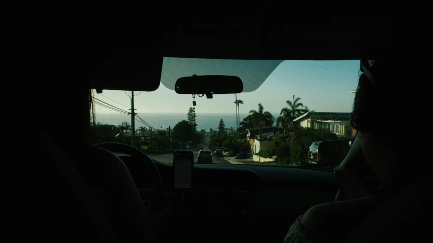 a person sitting in the back seat of a car, by Nathalie Rattner, ocean view, late morning, neighborhood, pov photo