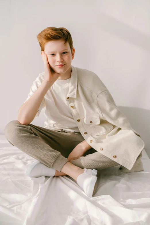 a young man sitting on top of a bed, trending on pexels, sadie sink, light cream and white colors, young child, smart casual