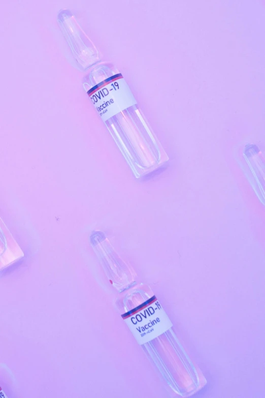 a group of vials sitting on top of a pink surface, thumbnail, covid, purples, medical labels