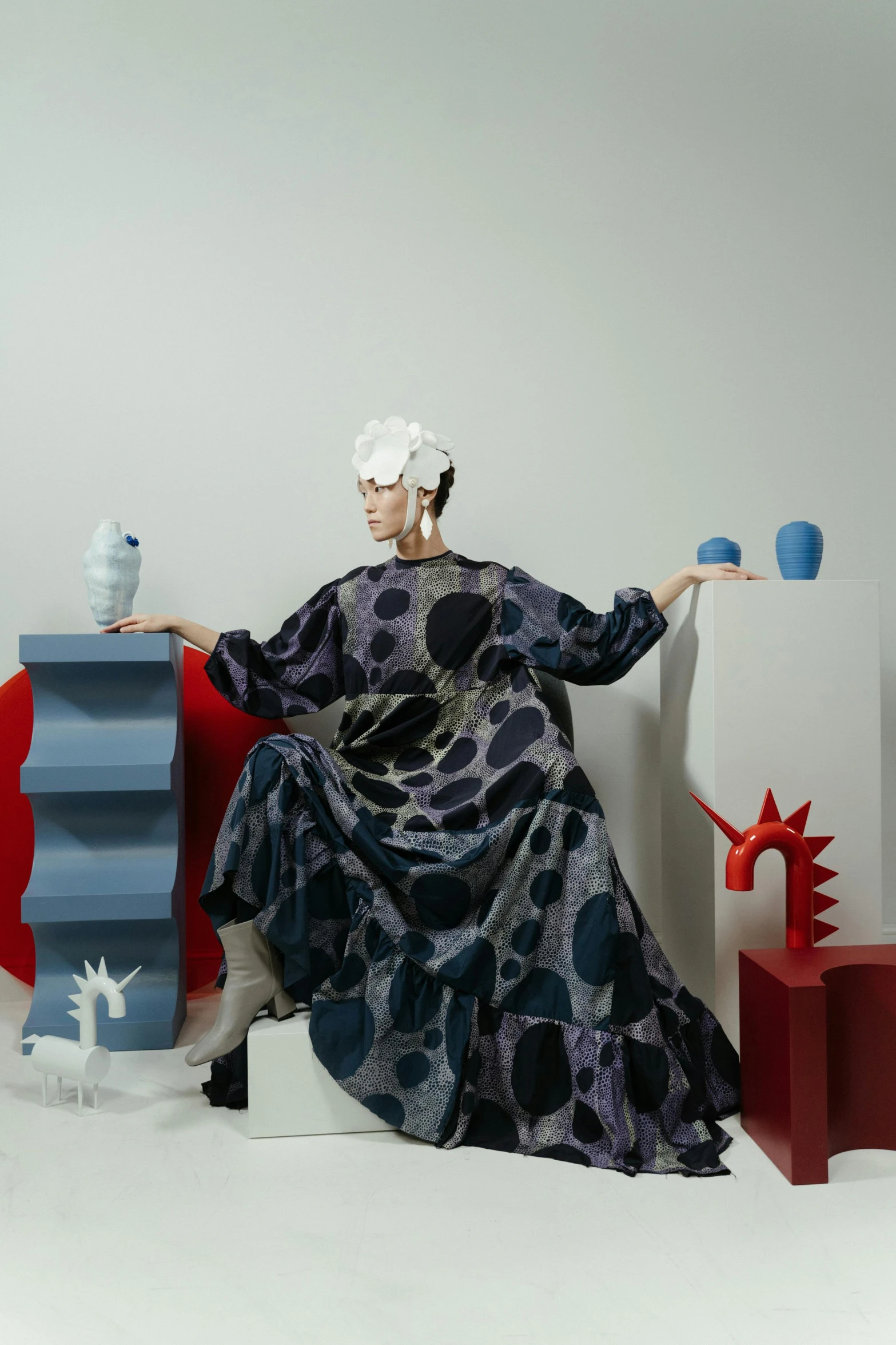 a woman in a blue dress sitting on a red chair, a surrealist sculpture, inspired by Gao Cen, maximalism, dots, voluminous sleeves, promotional image, full dress of lava showcase