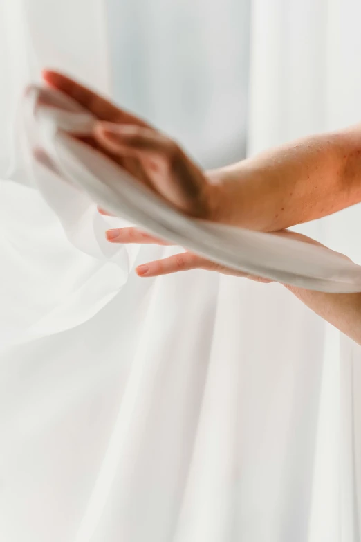 a woman standing in front of a white curtain, by Ruth Simpson, unsplash, visual art, flowing silk sheets, white bandages on fists, twirling, close up details