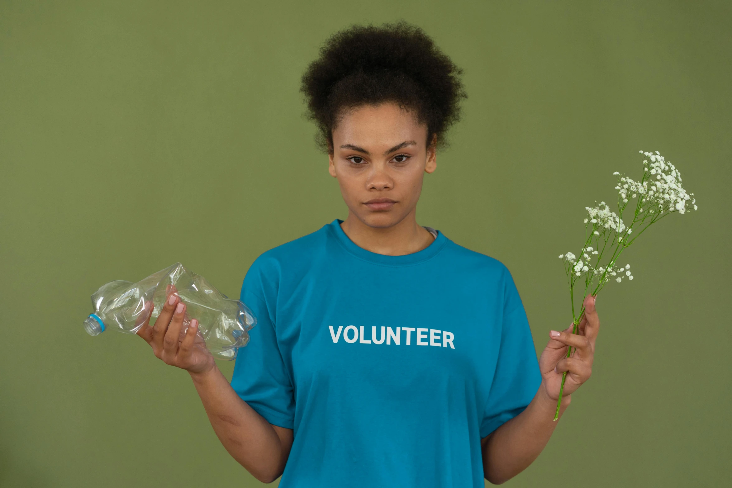 a woman holding a bunch of flowers in one hand and a plastic bottle in the other, pexels contest winner, minimalism, wearing a marijuana t - shirt, cyan and green, kara walker, sustainability