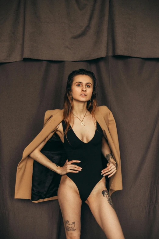 a woman in a black bodysuit posing for a picture, inspired by Elsa Bleda, pexels contest winner, renaissance, brown jacket, in front of white back drop, maxim sukharev, is wearing a swimsuit