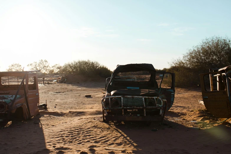 a couple of trucks that are sitting in the dirt, by Daniel Lieske, hurufiyya, sun shines down on the car, the lost beach, low quality photo, julian ope