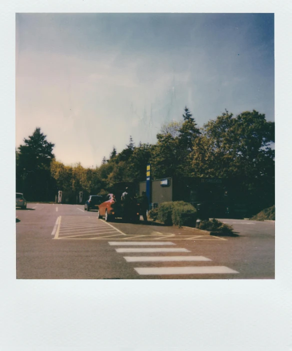 a car is parked on the side of the road, a polaroid photo, unsplash, convenience store, some trees in the corner, hi-res scan, crosswalk