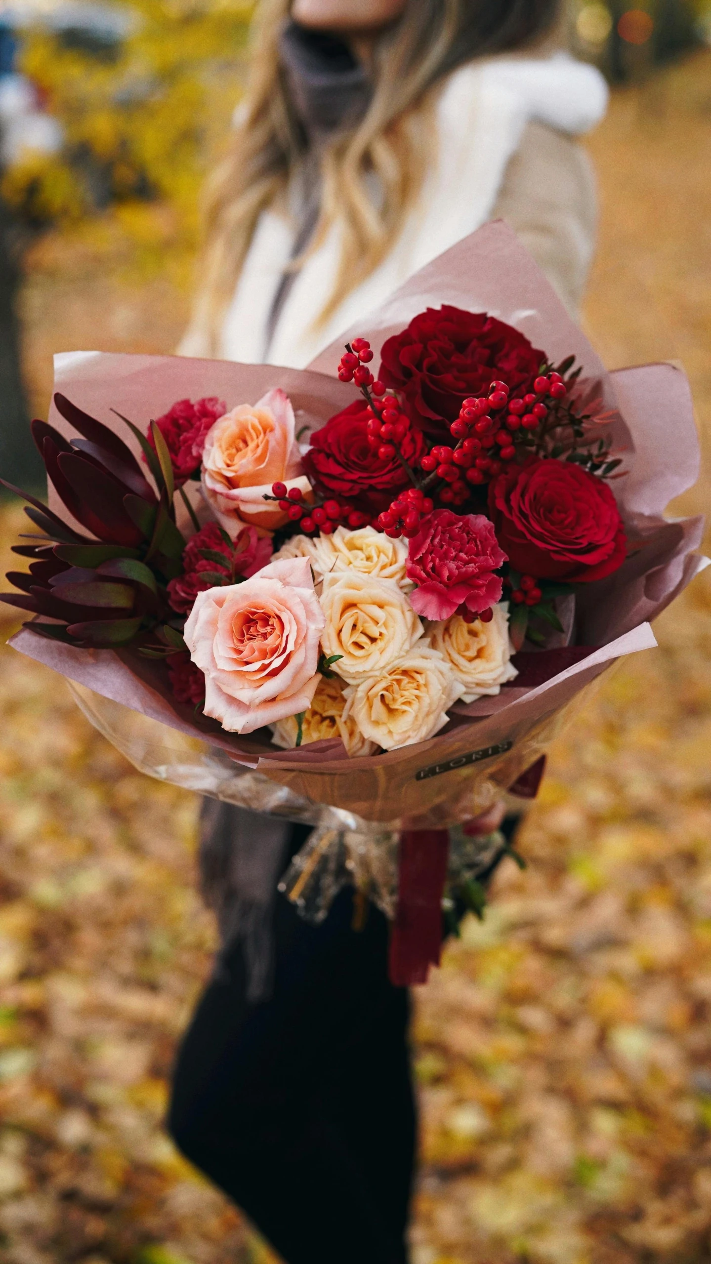 a woman holding a bouquet of flowers in a park, a photo, by Niko Henrichon, red and brown color scheme, no cropping, comforting, festive