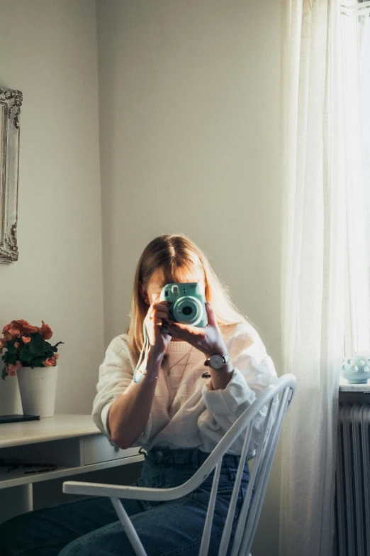 a woman sitting in a chair taking a picture of herself, a picture, inspired by Elsa Bleda, unsplash contest winner, in white room, home album pocket camera photo, a blond, camera bloom