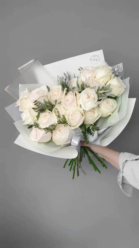 a woman holding a bouquet of white roses, a pastel, inspired by François Boquet, pixabay, on a gray background, angled shot, cream paper, glittering and soft