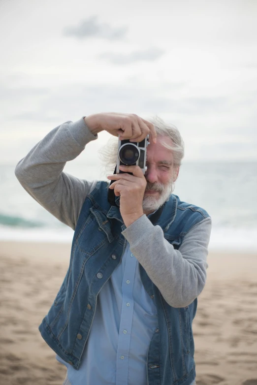 a man taking a picture of himself on the beach, a photo, by Peter Churcher, unsplash, photorealism, long grey beard, lovingly looking at camera, photo in color, rolleiflex