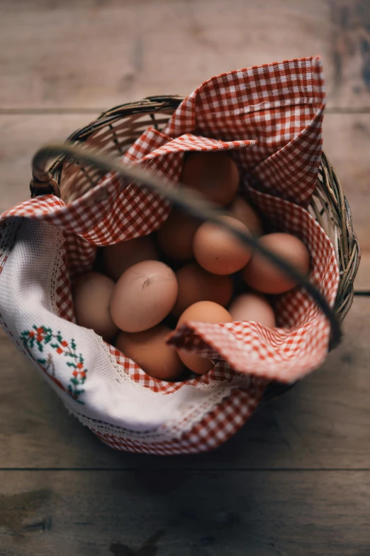 a basket filled with eggs on top of a wooden table, unsplash, 💋 💄 👠 👗, linen, chicken, laura watson