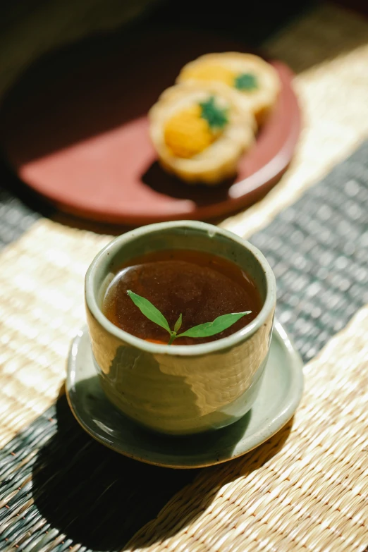 a cup of tea sitting on top of a table, inspired by Miyagawa Chōshun, close up food photography, brown gravy, sage, thumbnail