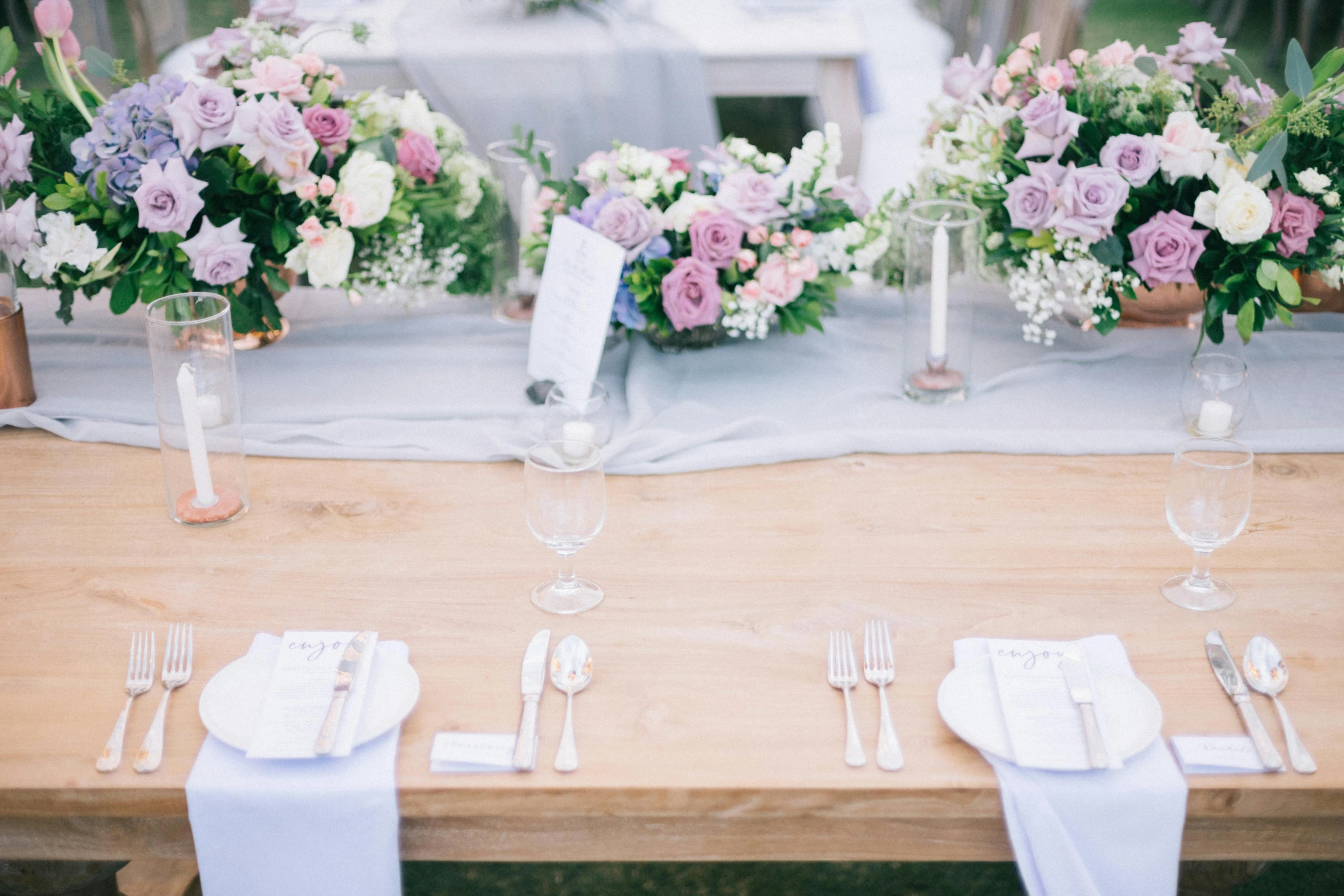 a wooden table topped with vases filled with flowers, unsplash, romanticism, lilac, white and pale blue toned, overflowing feast buffet table, exterior shot