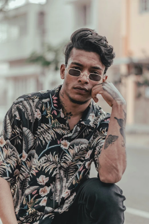 a man sitting on a curb talking on a cell phone, inspired by Byron Galvez, trending on pexels, body covered in floral tattoos, dark shades, button up shirt, tropics