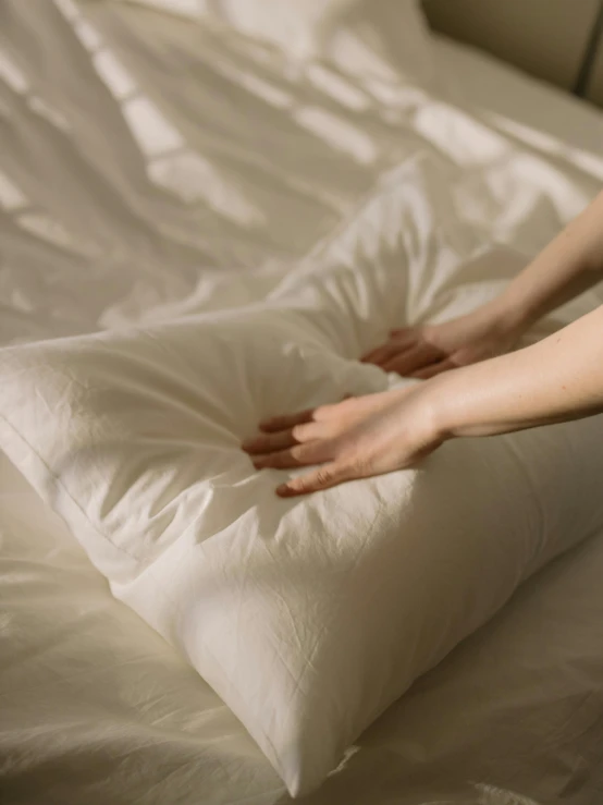 a person placing a pillow on top of a bed, inspired by Elsa Bleda, trending on unsplash, pale milky white porcelain skin, very long arms, high angle close up shot, ilustration