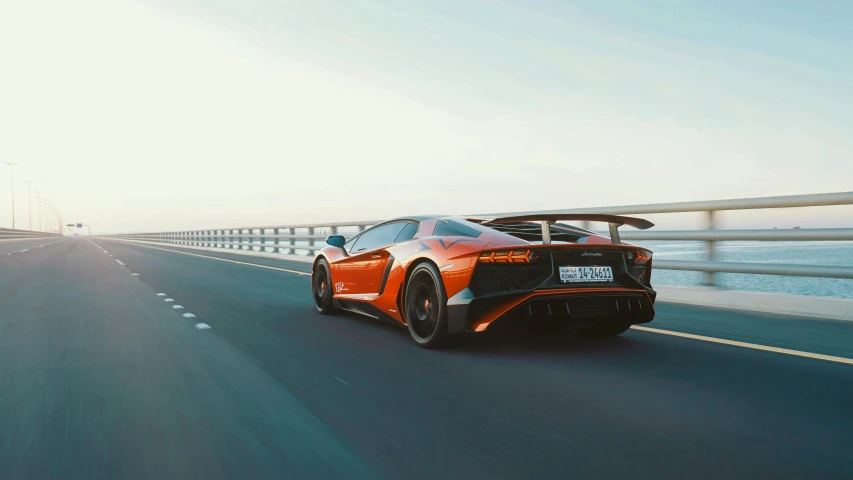 an orange sports car driving down a highway, inspired by Mike Winkelmann, pexels contest winner, hyperrealism, lamborghini aventador photoshoot, panoramic anamorphic, 8k resolution”